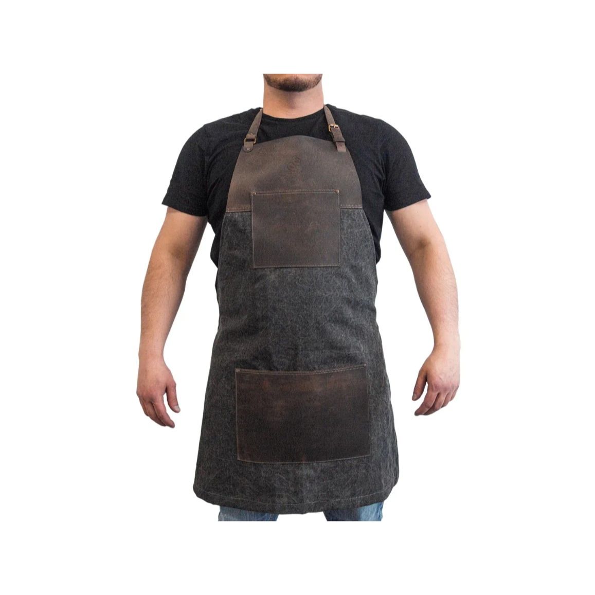 A person wearing a brown canvas apron with leather patch pockets and decorative metal rivets.